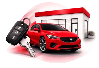 Red sedan in front of a car dealership with a key fob in the foreground.